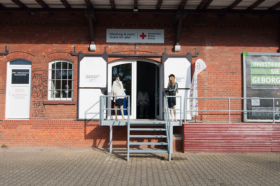 Das Bild zeigt den Eingang zum Kleiderladen. Vor dem Laden befindet sich eine Treppe.